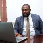 Un homme d'âge moyen en costume, travaillant sur un pc dans un bureau.
